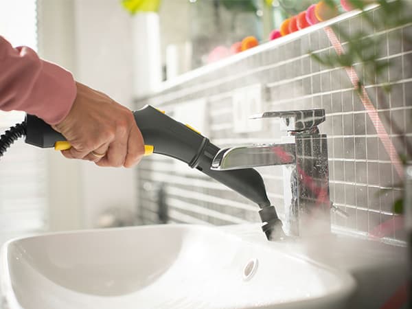 Professionell ångtvätt av badrumshandfat för att ta bort kalkfläckar